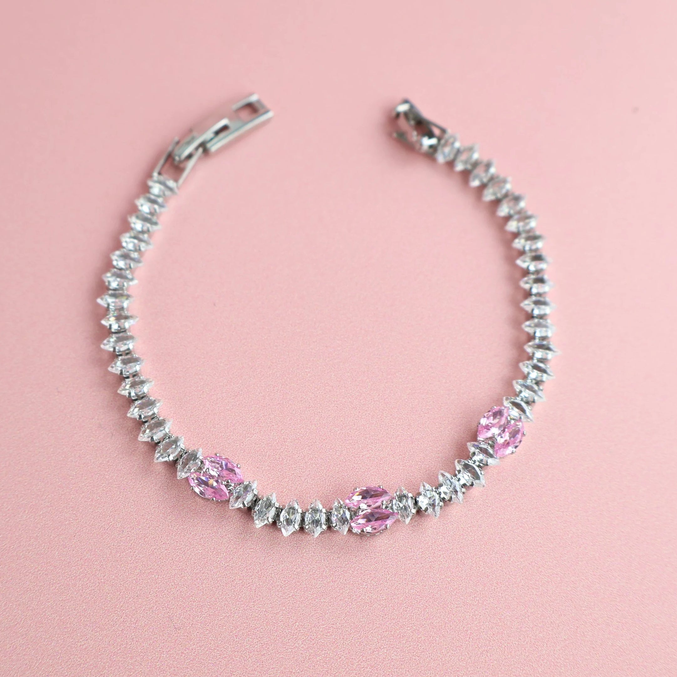 Silver bracelet with pink and clear zirconia stones on pink background